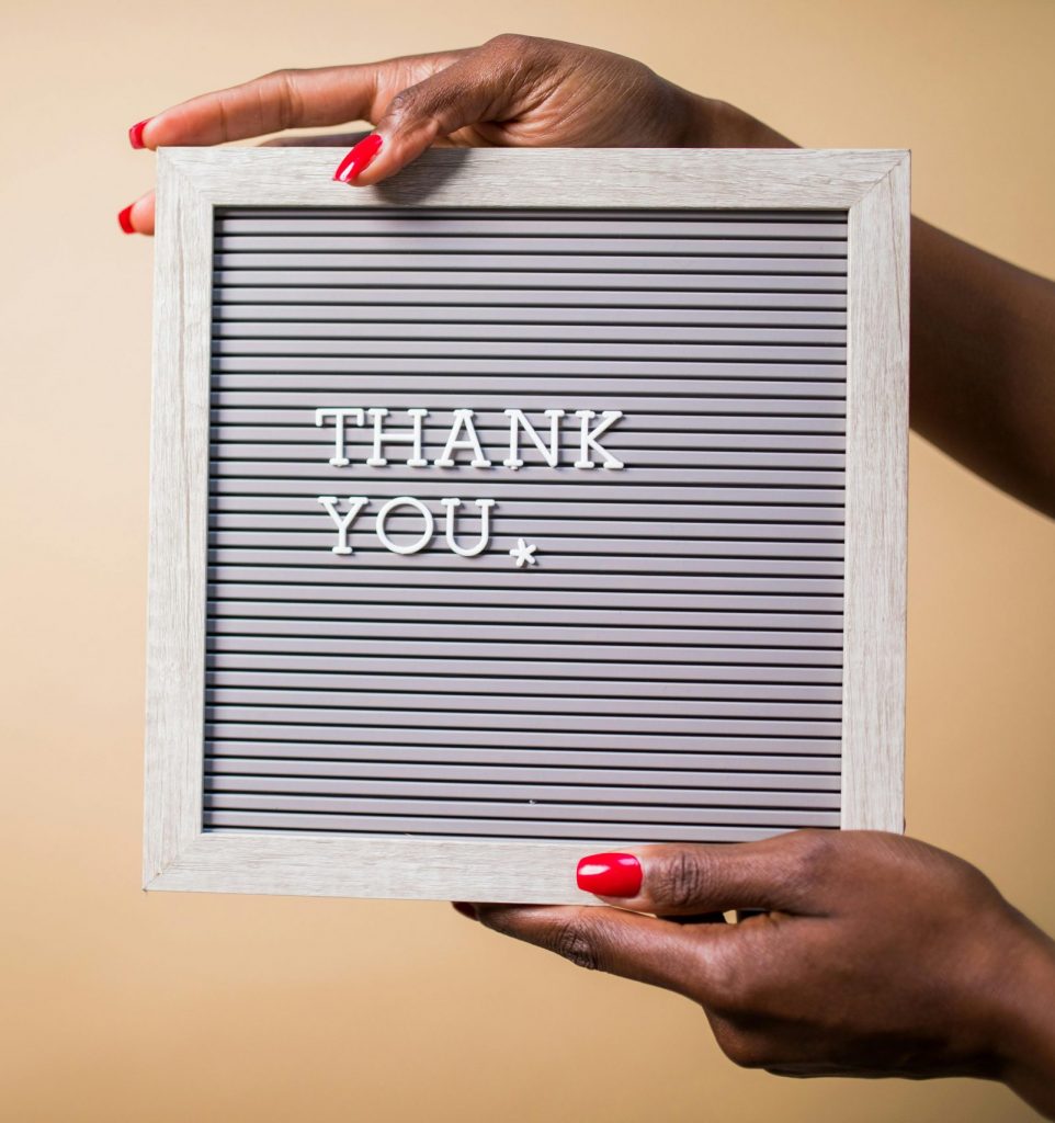 photo de RDNE de Stock project. Photo de main d'une femme noire tenant un panneau avec écrit : "Thank you."